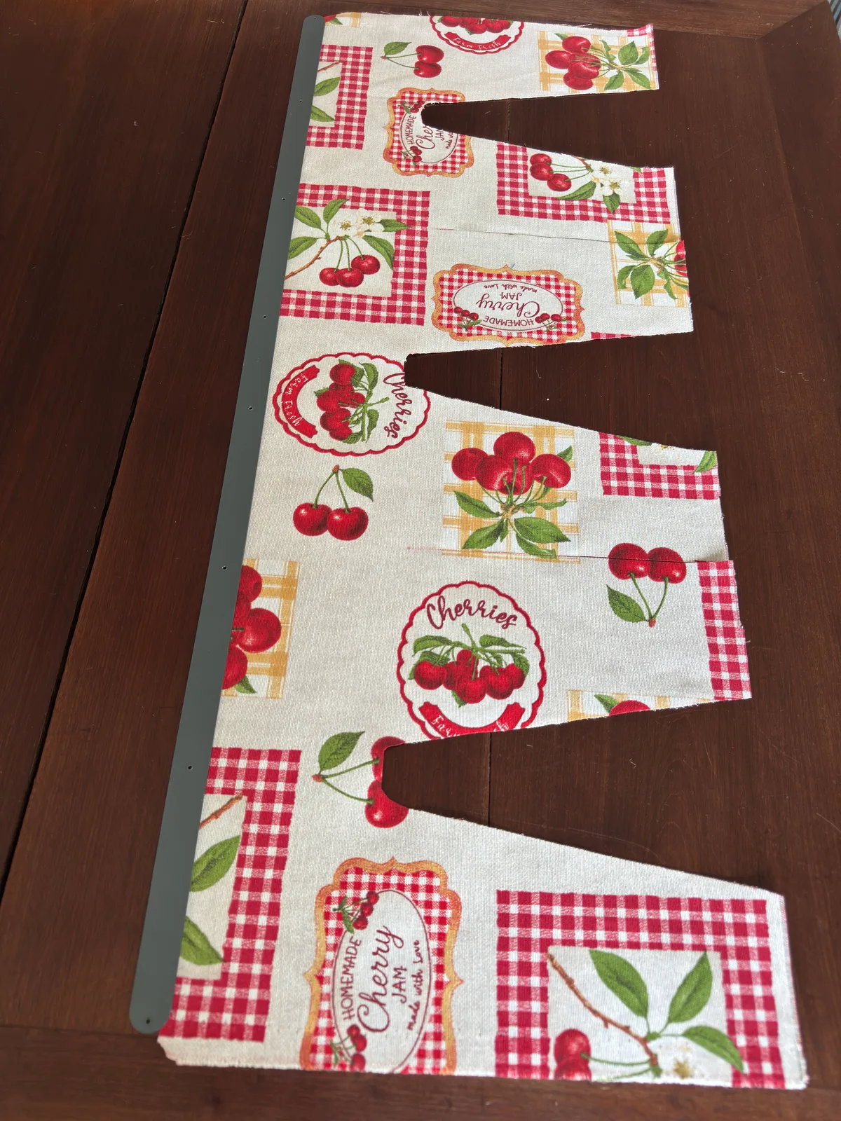 A cherry-print fabric cut to the Gush-Tuss privacy curtain pattern, before installation