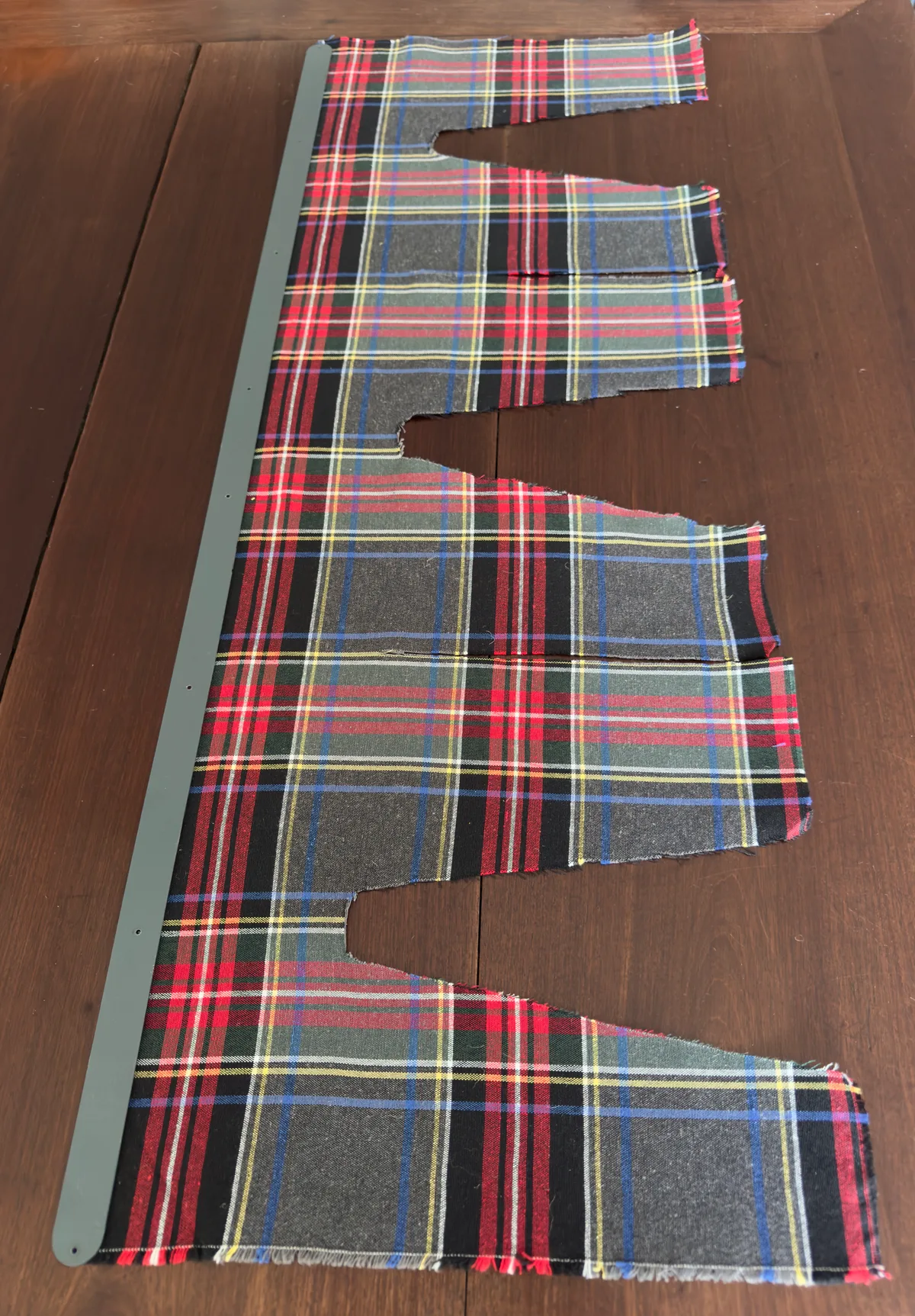 A plaid-pattern fabric cut to the Gush-Tuss privacy curtain pattern, before installation